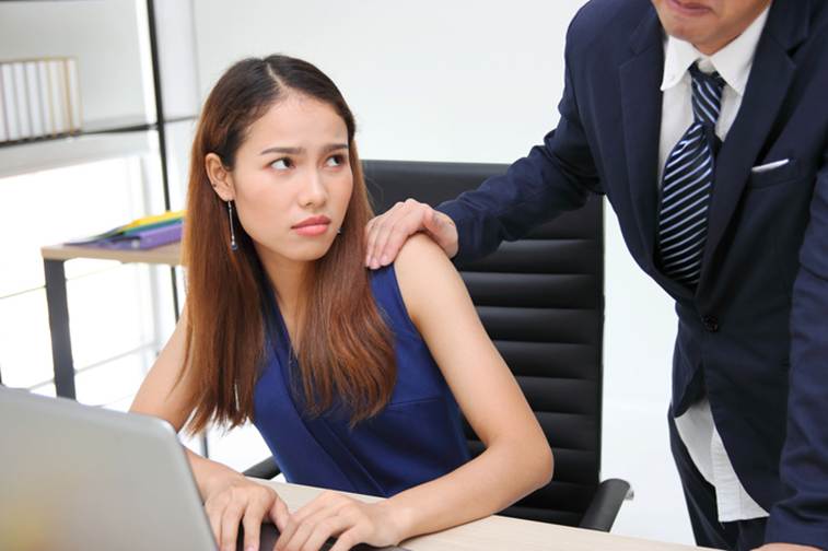 Man with hand on female employee's shoulder - Sexual Discrimination